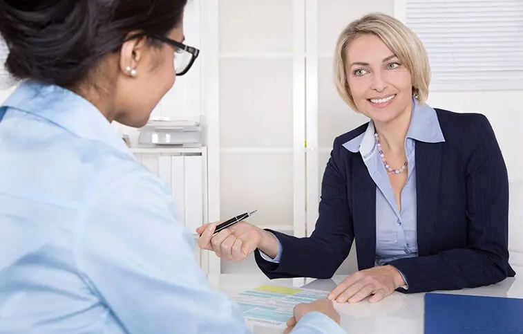 A woman shaking hands with another person at a table.