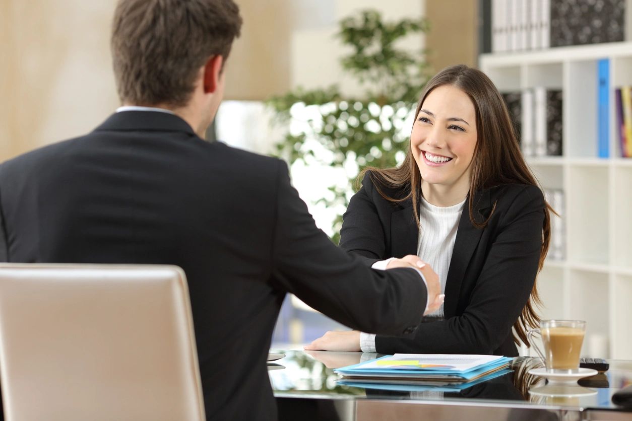 A man and woman shaking hands at an office meeting.